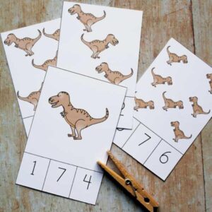 t rex count and clip cards with clothespin on a wooden table each card had a picture or few of trex dinosaur and then numbers to match below